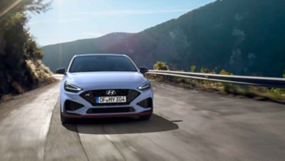 The new Hyundai i30 N driving in a hilly set in the colour Performance Blue.