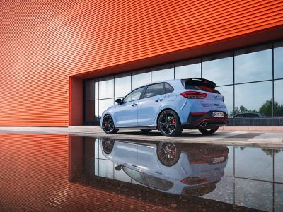 The new Hyundai i30 N performance hatchback parked next to a reflective surface	.