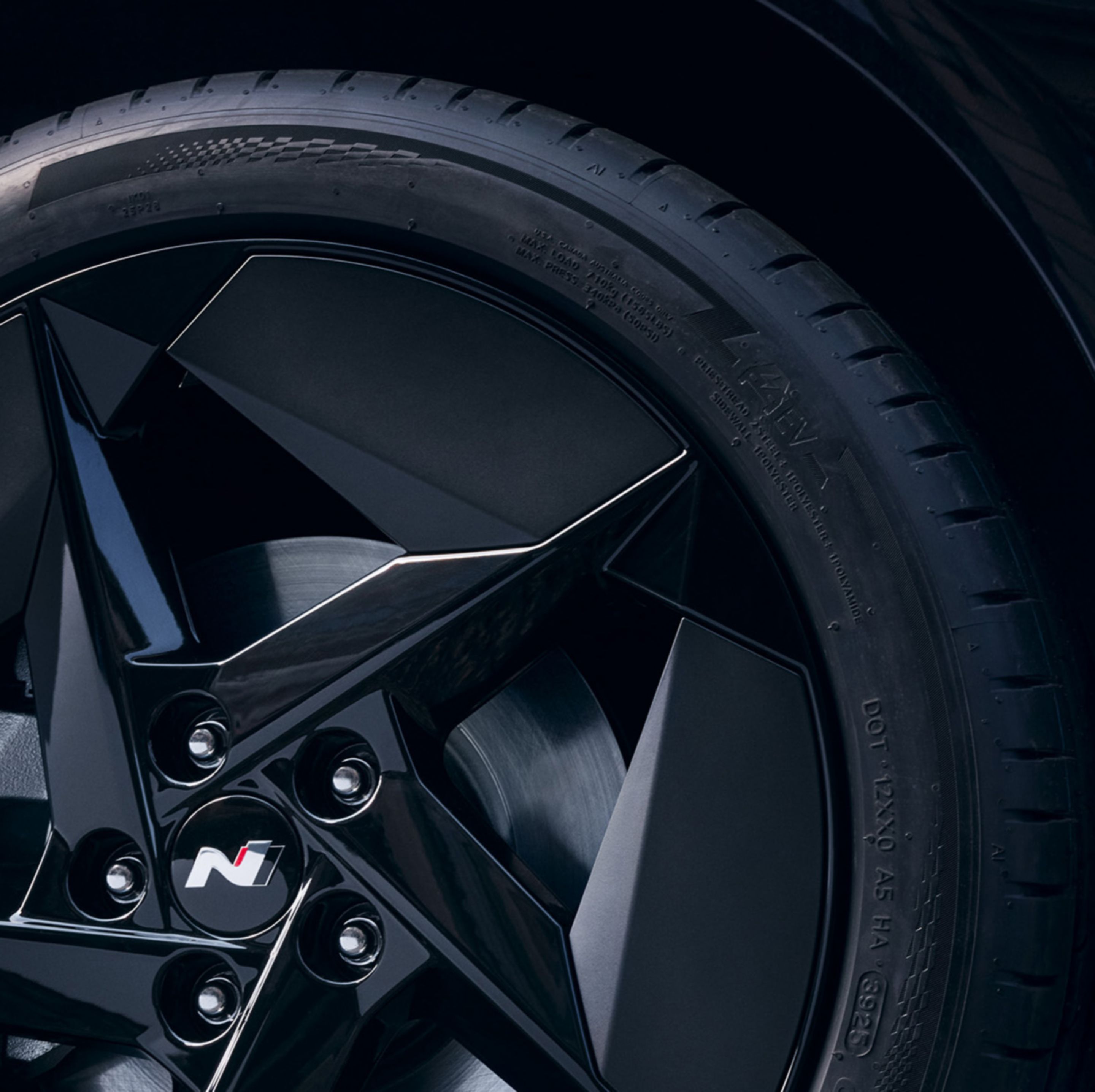 Wheel detail with black alloy rim featuring angular aero-inspired design.