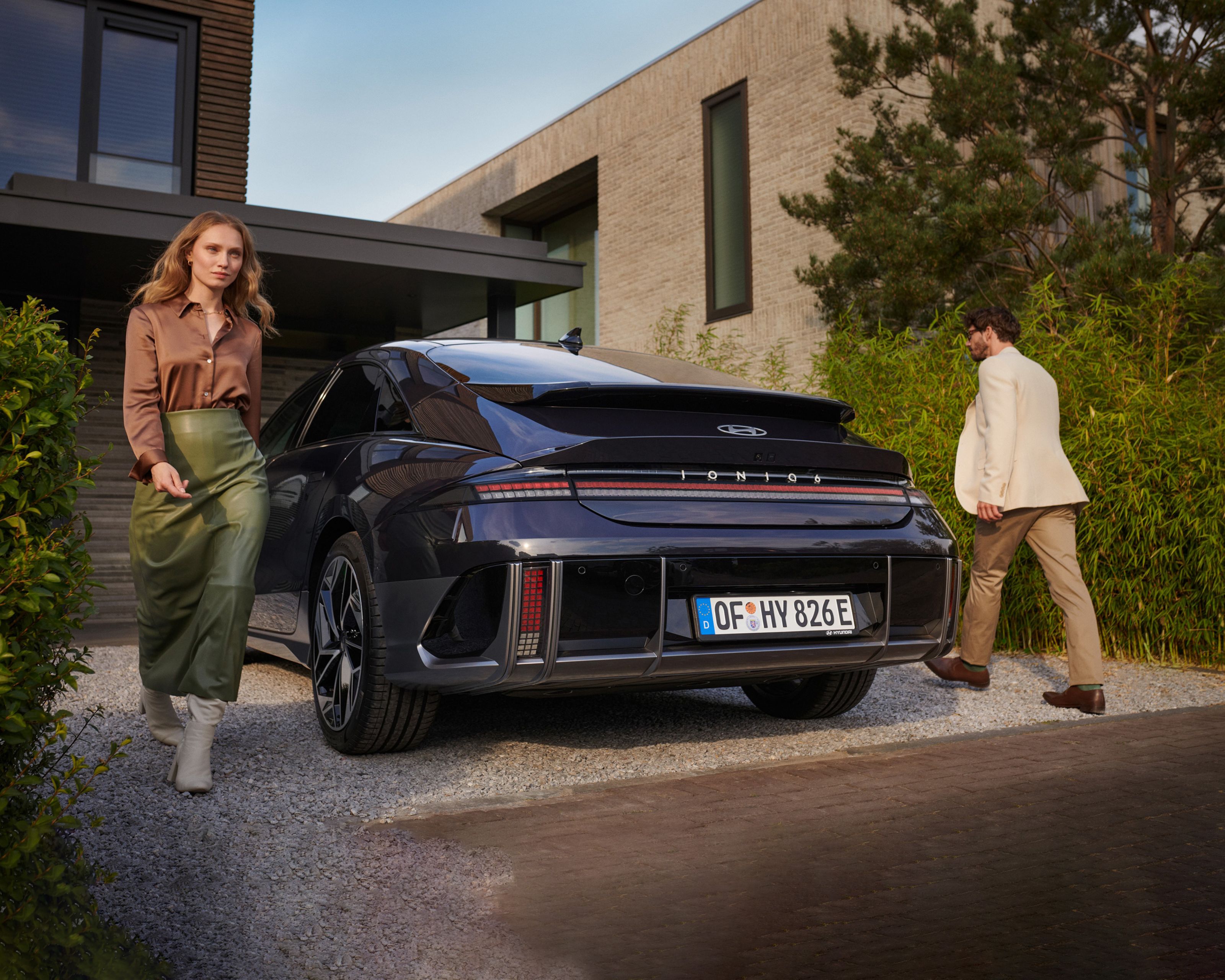 woman with brown t-shirt and a man standing next to the Hyundai IONIQ 6 