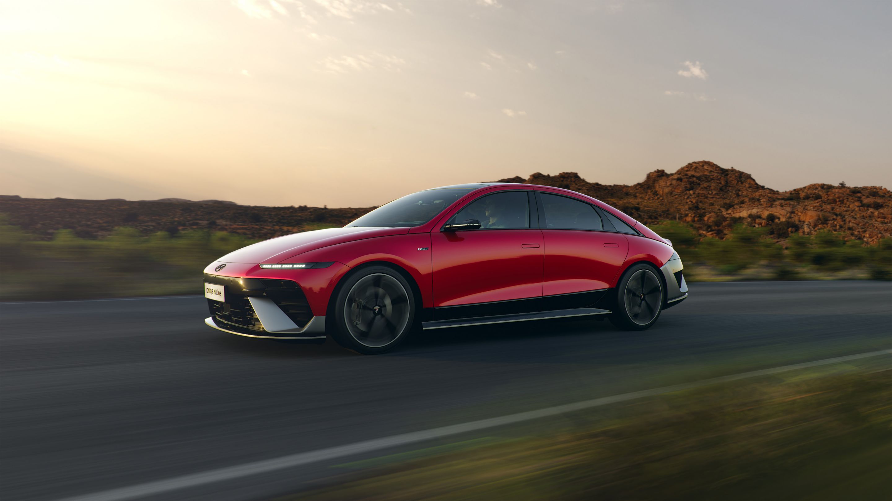 The new Hyundai IONIQ 6 N Line in red driving down a highway with hills in the background.&nbsp;