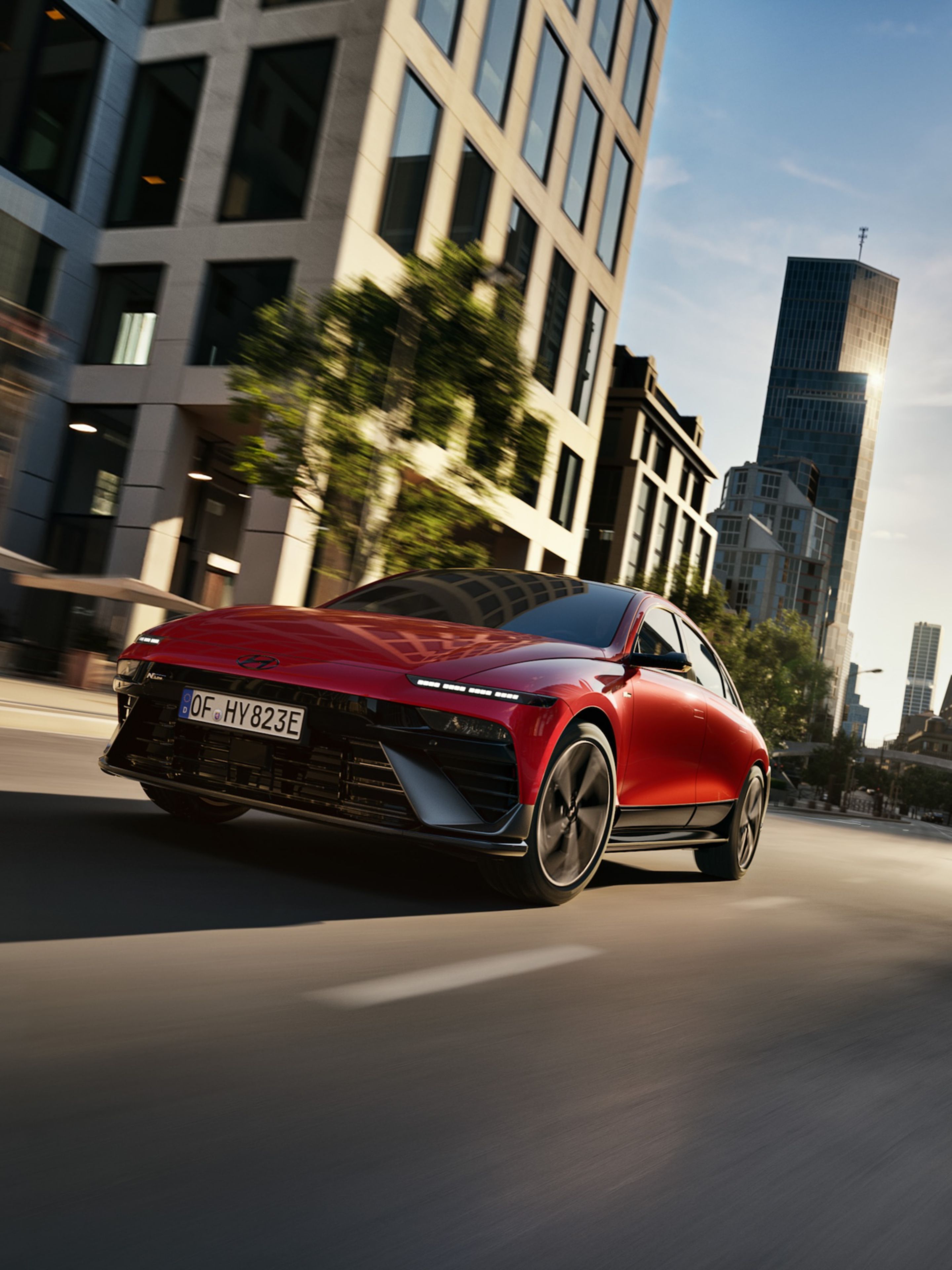  A red Hyundai IONIQ 6 N Line driving through a modern cityscape.