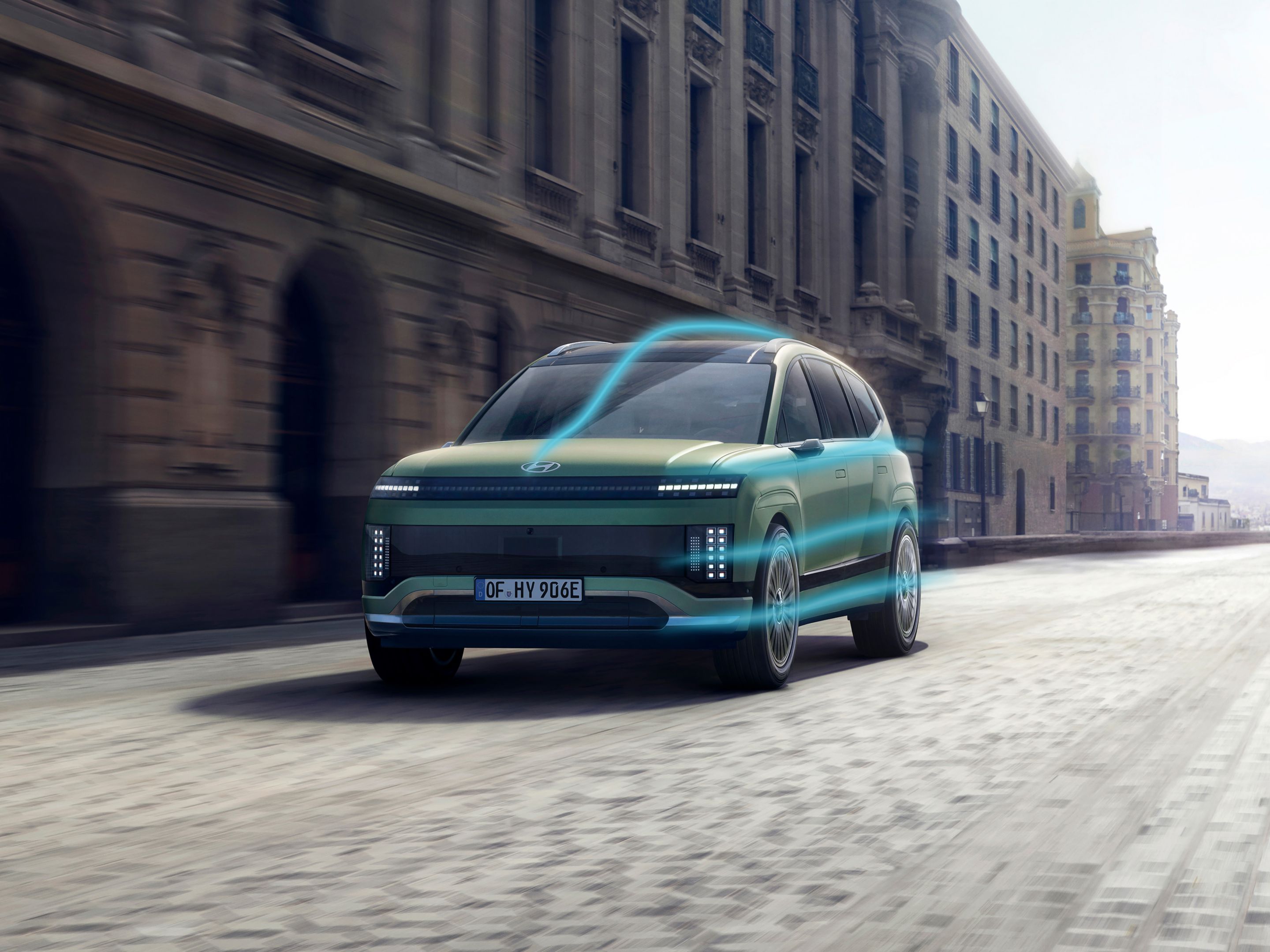 Hyundai IONIQ 9 driving through a city street with an aerodynamic flow graphic.