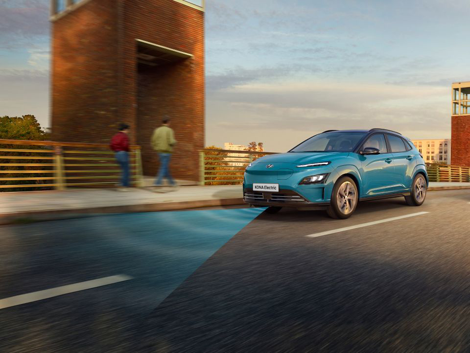 The new Hyundai Kona Electric with Forward Collision-Avoidance Assist driving over a bridge. 