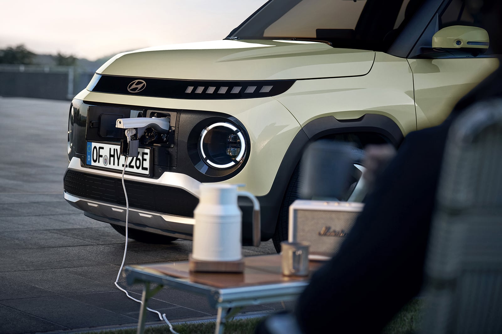Hyundai INSTER with a converter plugged into the exterior charging port for Vehicle-to-Load capability. 