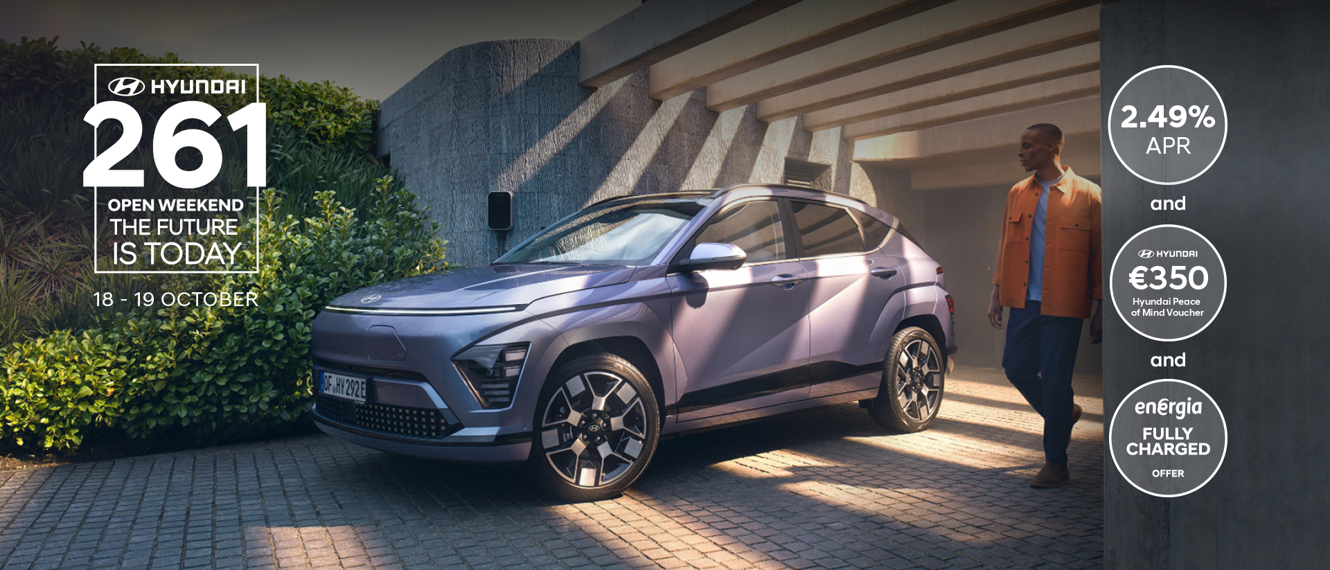 The Hyundai KONA Electric bathed in sunlight with a man walking away from a garage.