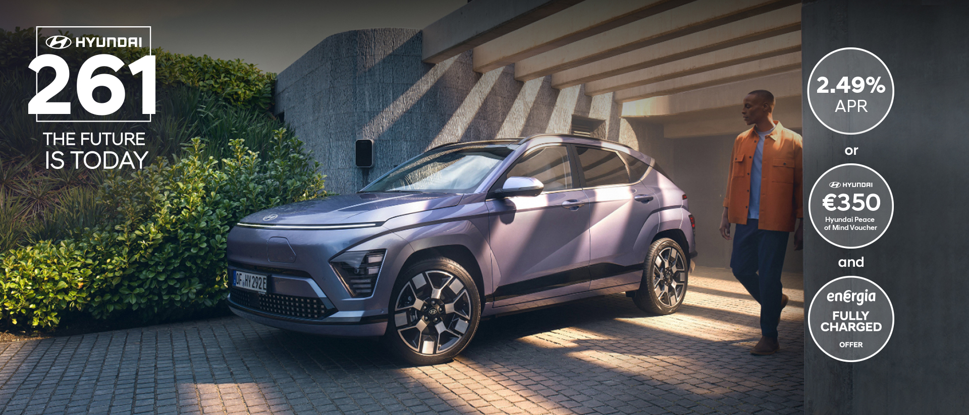 The Hyundai KONA Electric bathed in sunlight with a man walking away from a garage.