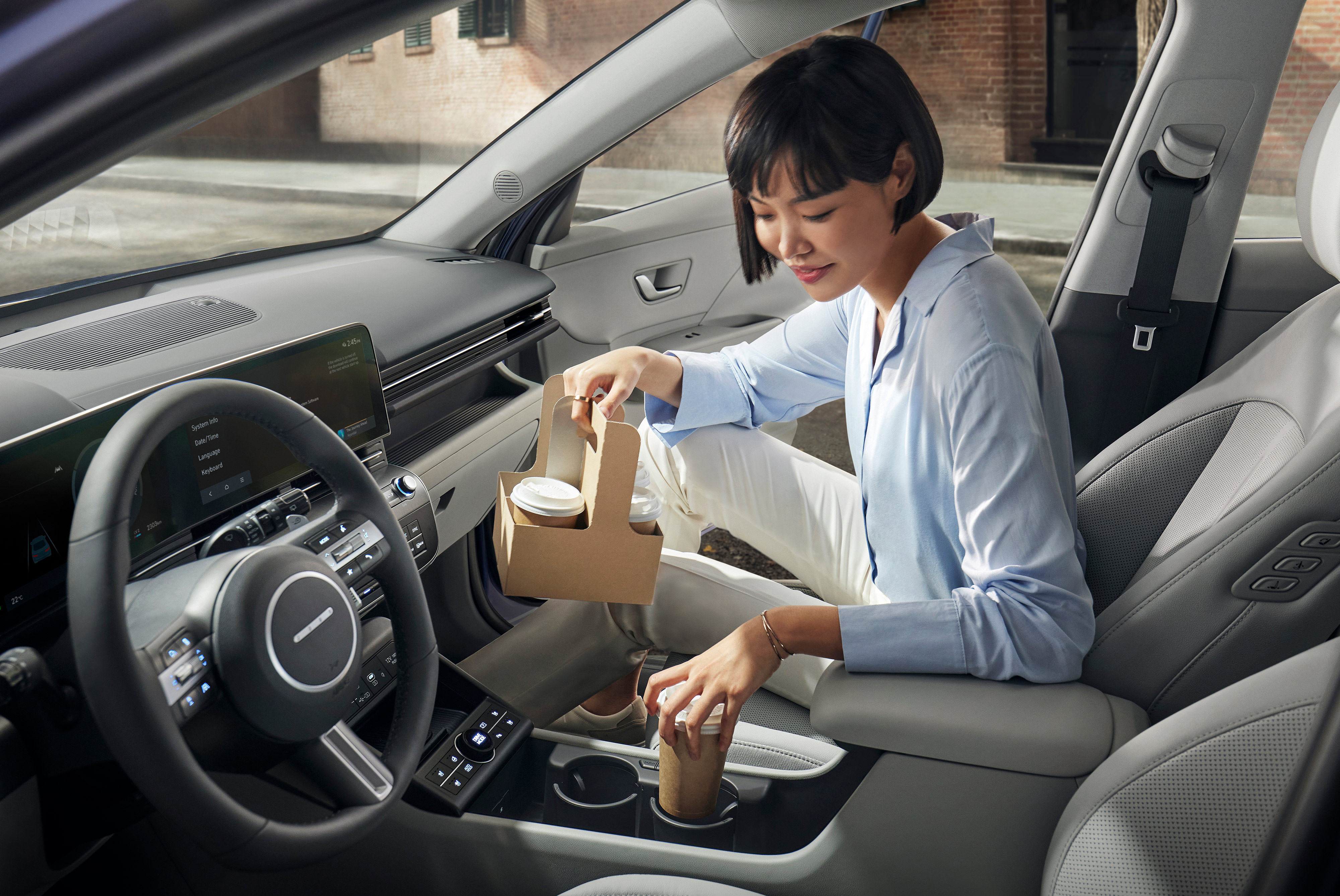 A woman putting her coffee on one of the rotational cup holders of the Hyundai KONA.