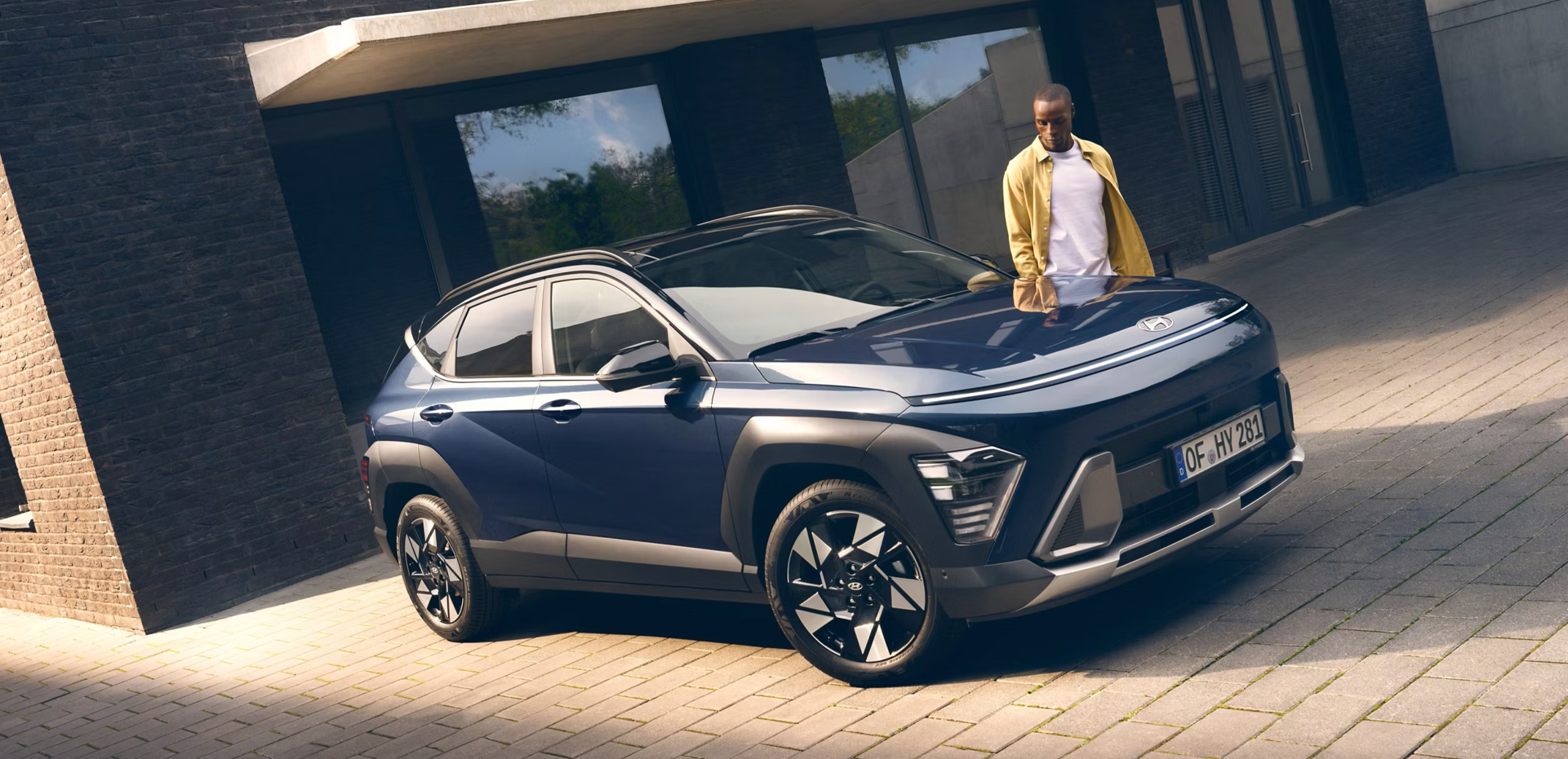 The all-new Hyundai KONA in blue parked next to a men with yellow shirt.