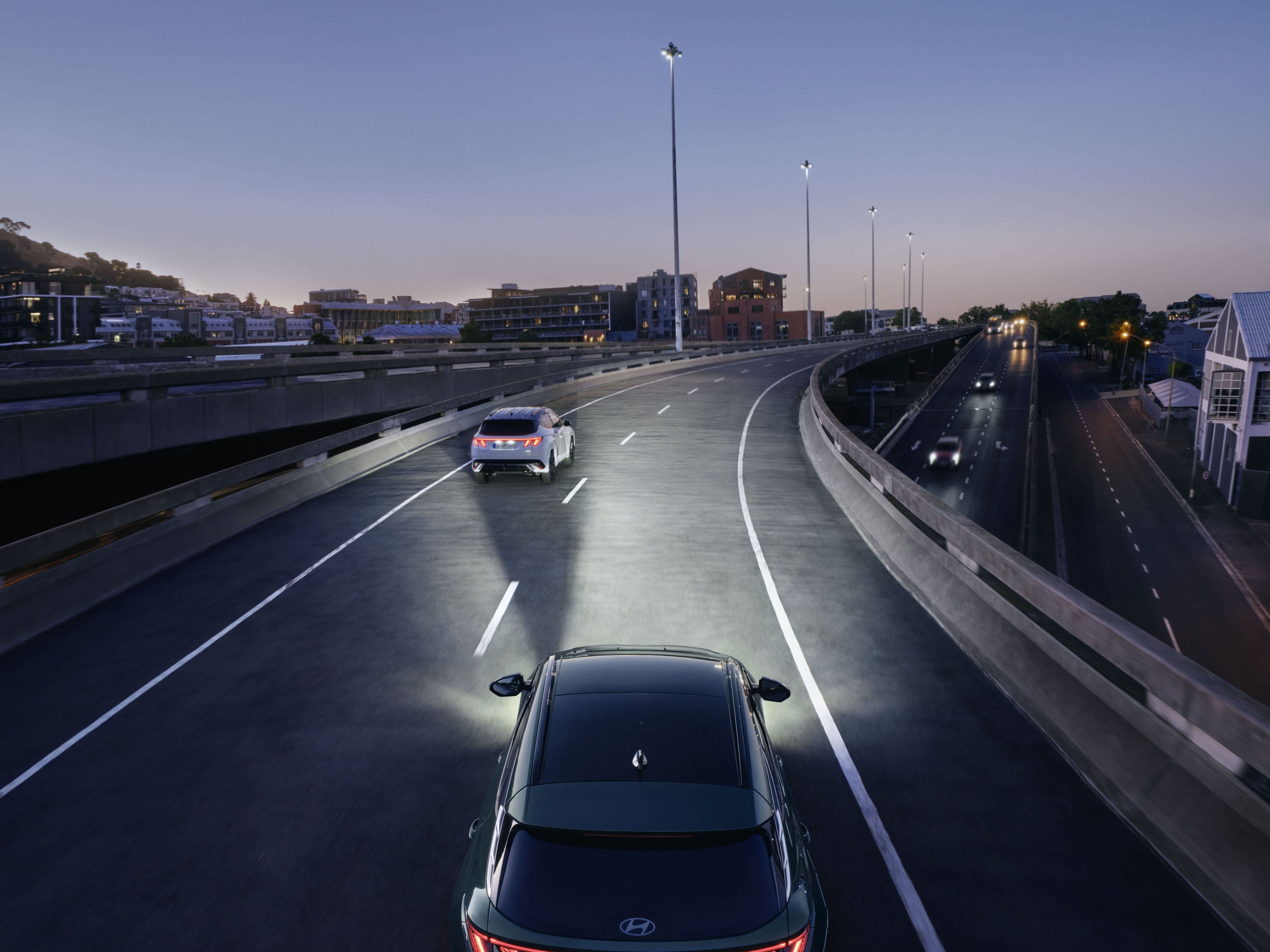 Hyundai TUCSON Hybrid seen from above as it drives in dark conditions with lights on.