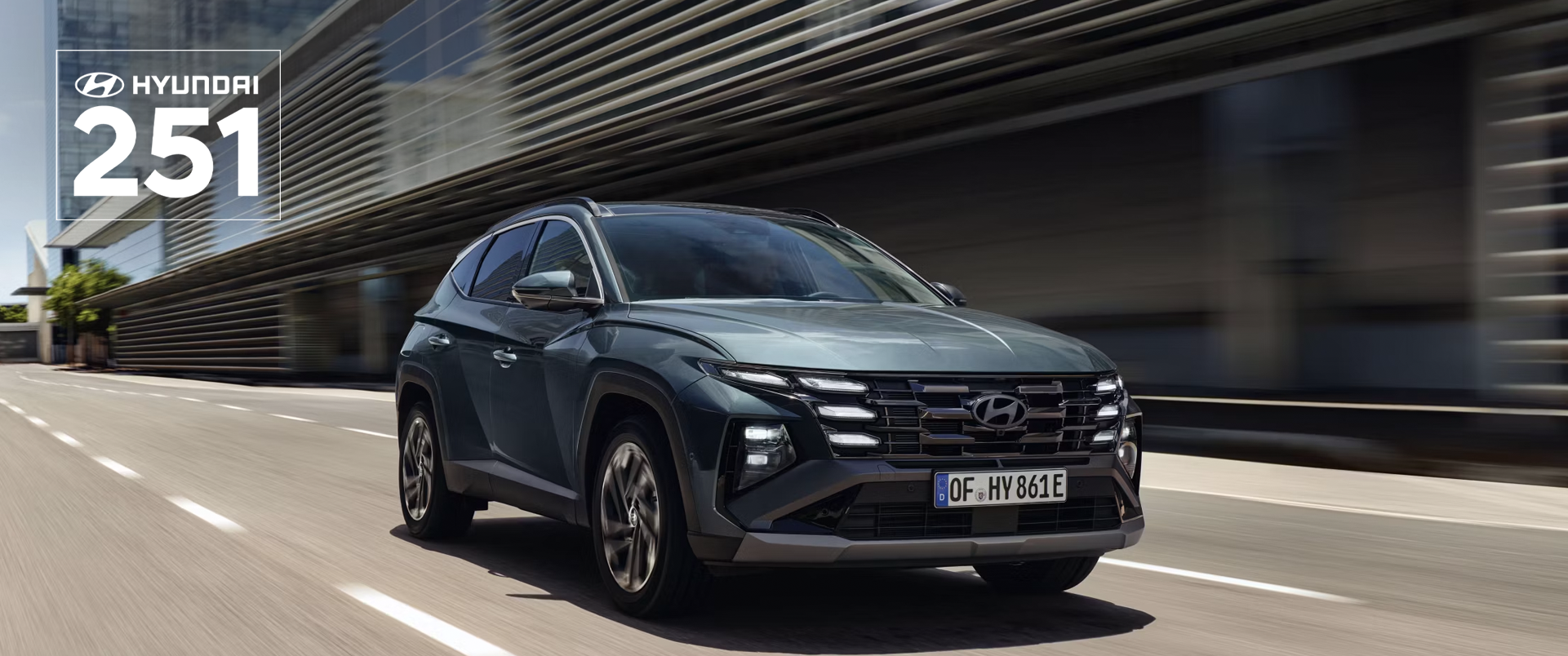 The Hyundai TUCSON Plug-in Hybrid driving down a city street with modern buildings visible.