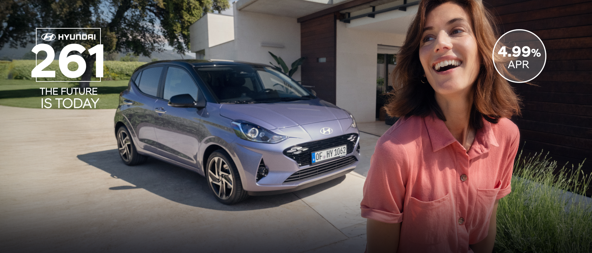 A woman walking and smiling in front of the new Hyundai i10.