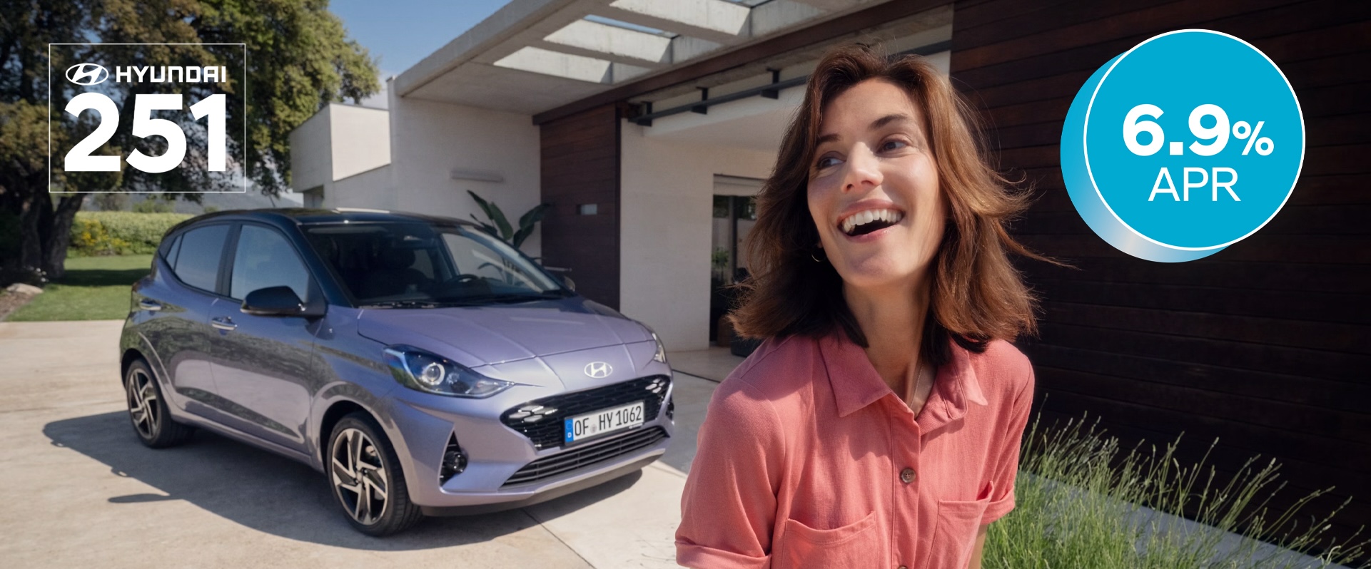 A woman walking and smiling in front of the new Hyundai i10.