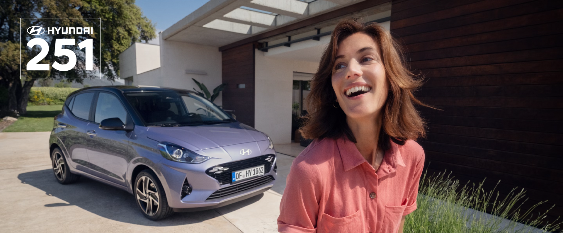 A woman walking and smiling in front of the new Hyundai i10.