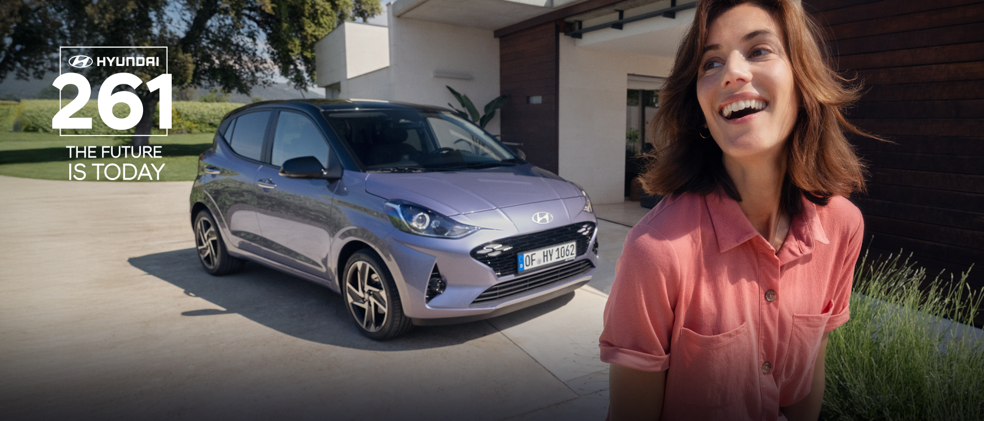 A woman walking and smiling in front of the new Hyundai i10.