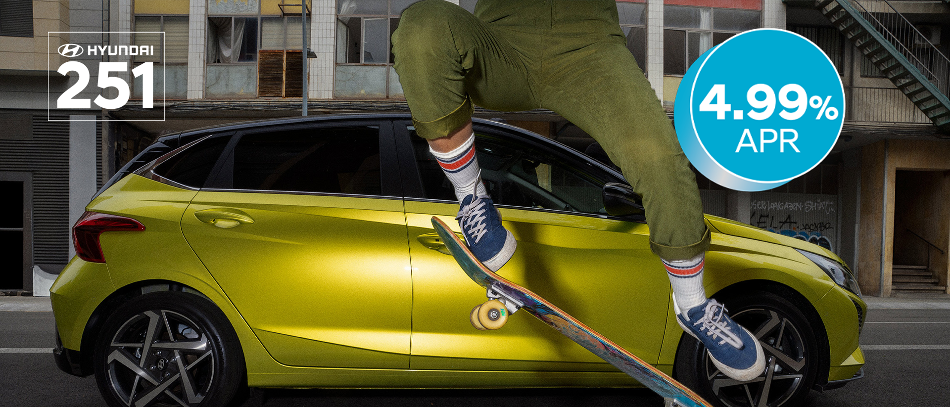 A young woman skateboarding in the street with a Hyundai i20 in the background.	