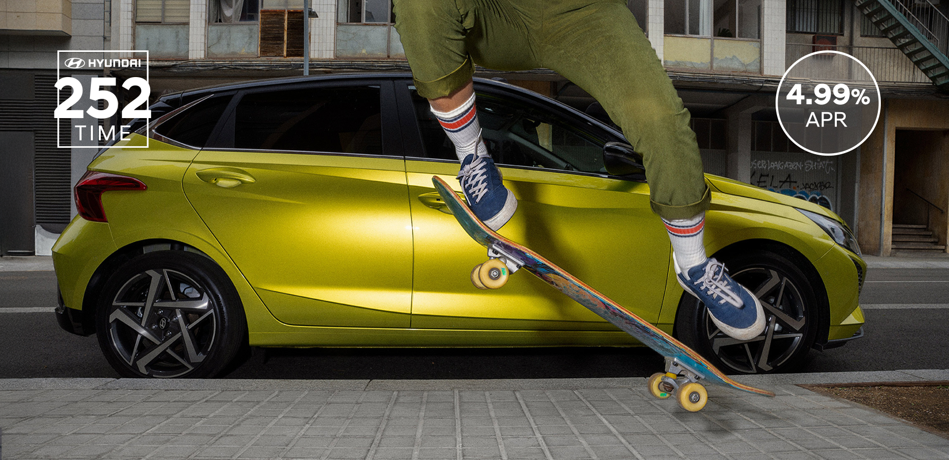 A young woman skateboarding in the street with a Hyundai i20 in the background.	