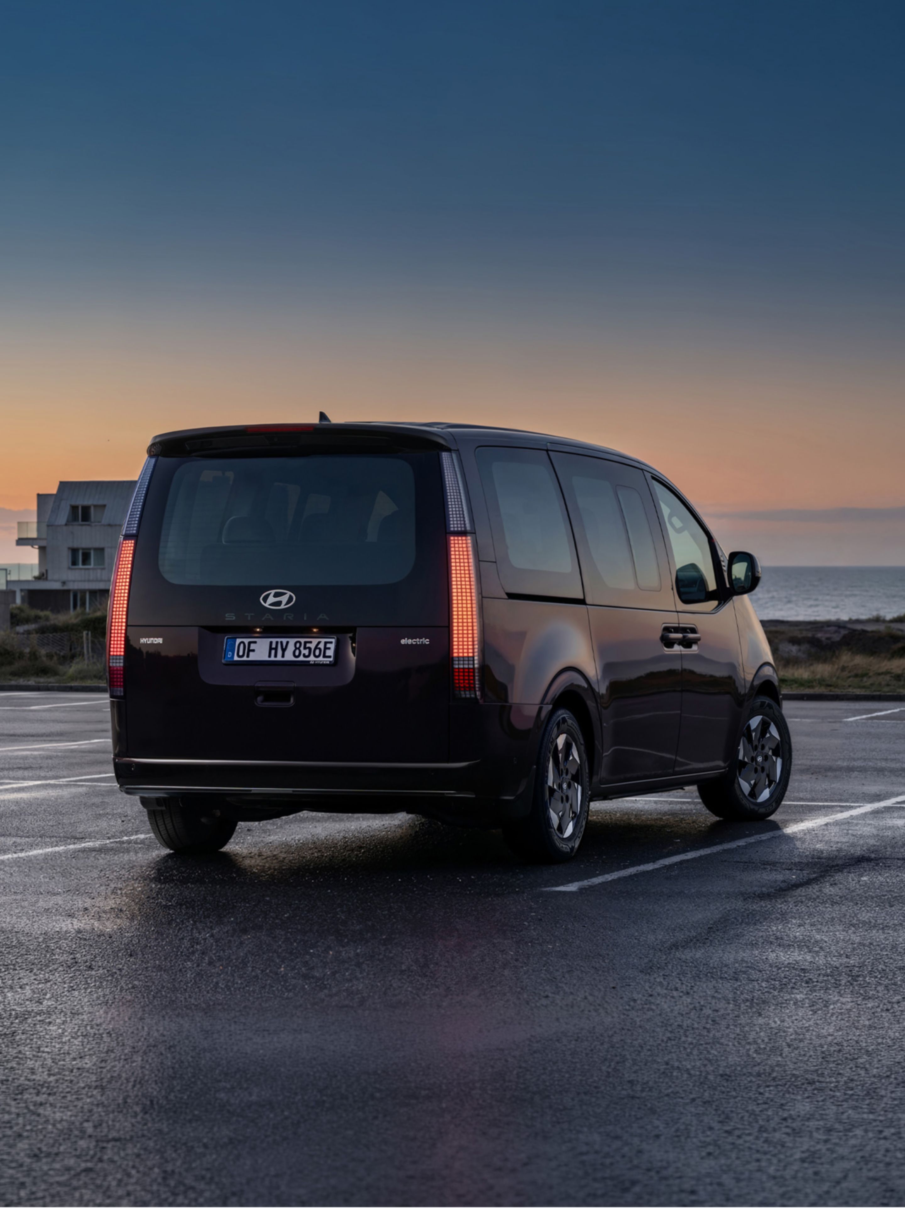 Hyundai STARIA Electric viewed from the front, with a sunset in the background.