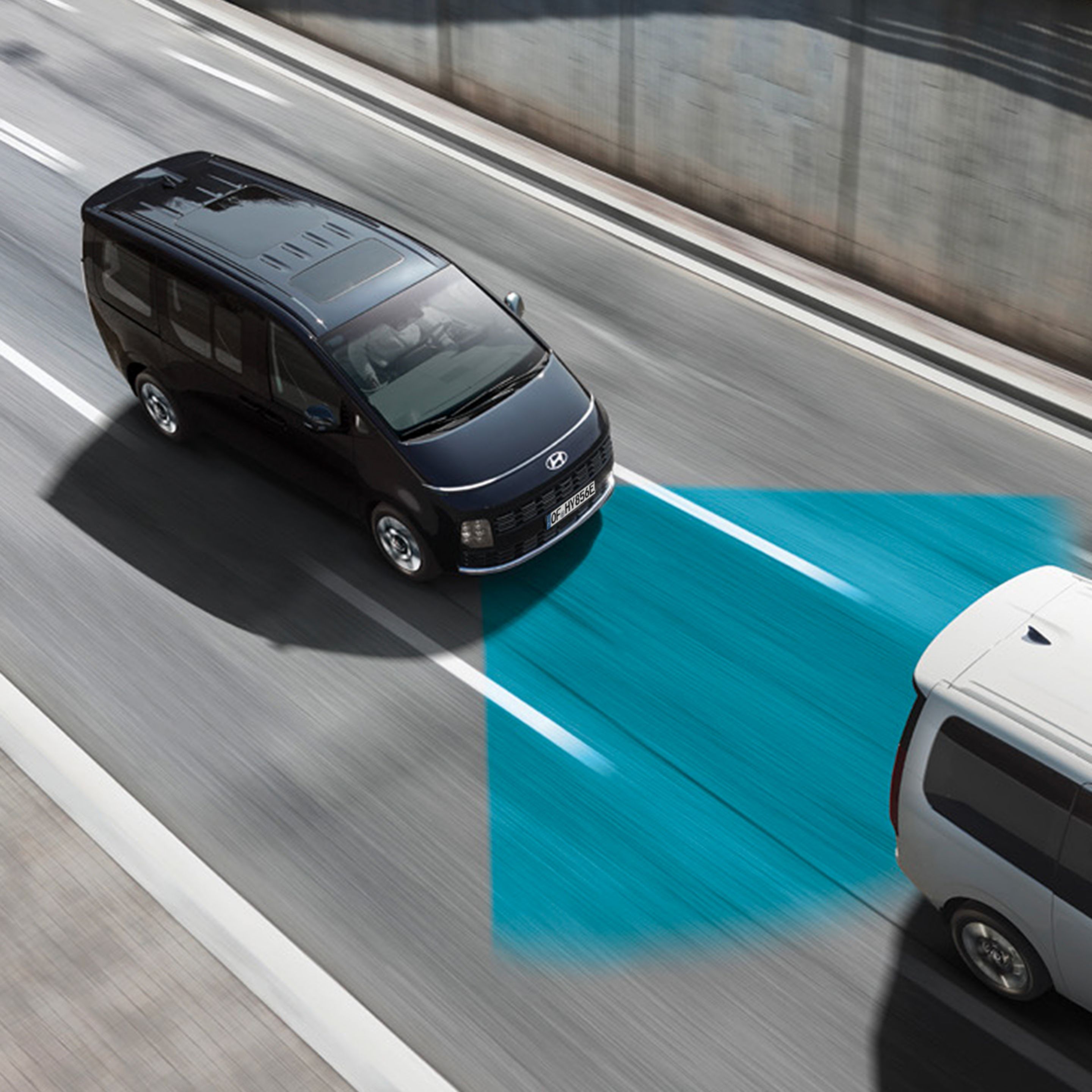 Hyundai STARIA van driving on a highway with an adjacent lane highlighted to indicate driver‑assistance functionality.
