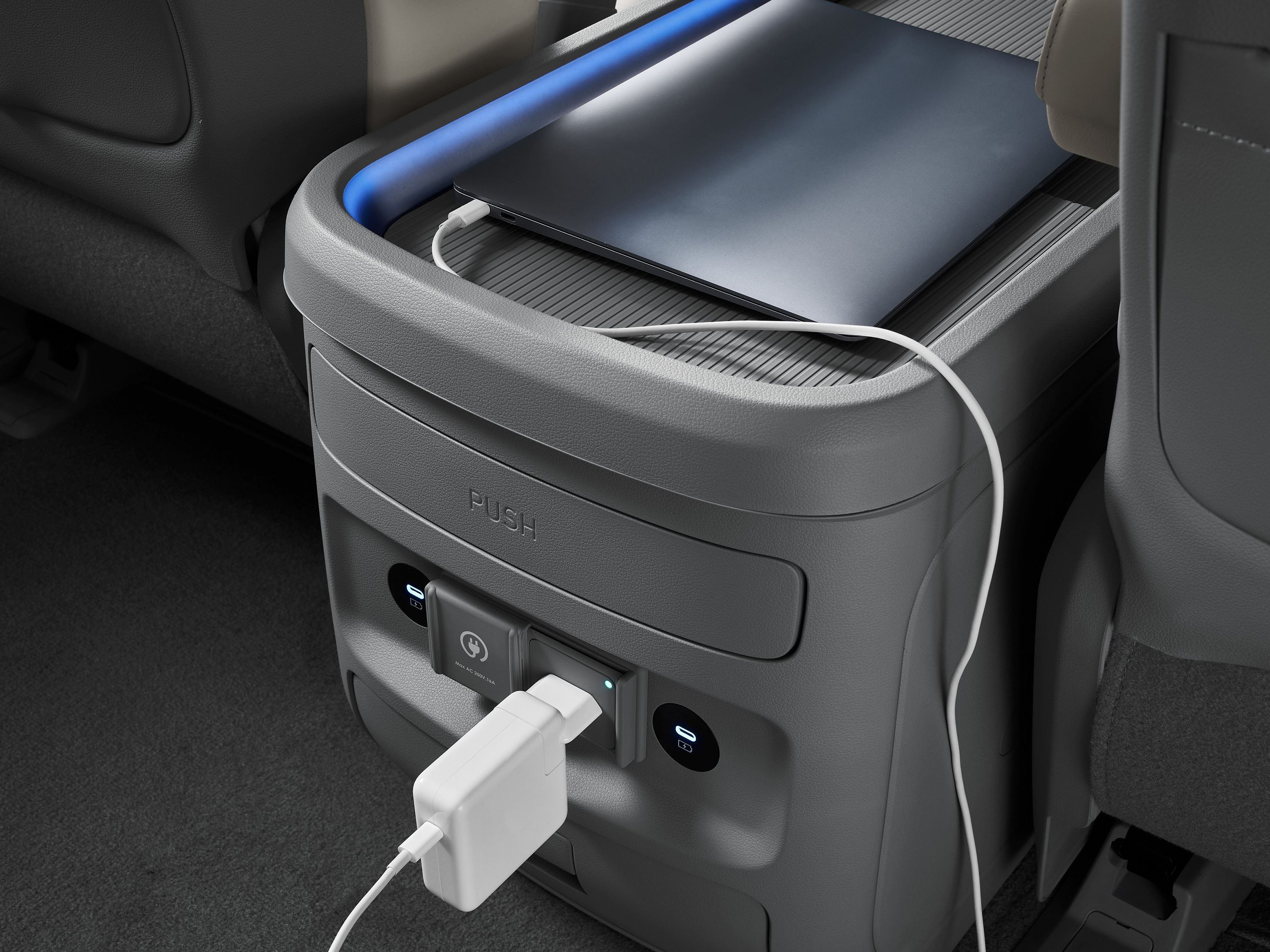 Hyundai STARIA Electric rear console with USB ports and power outlet charging a device.