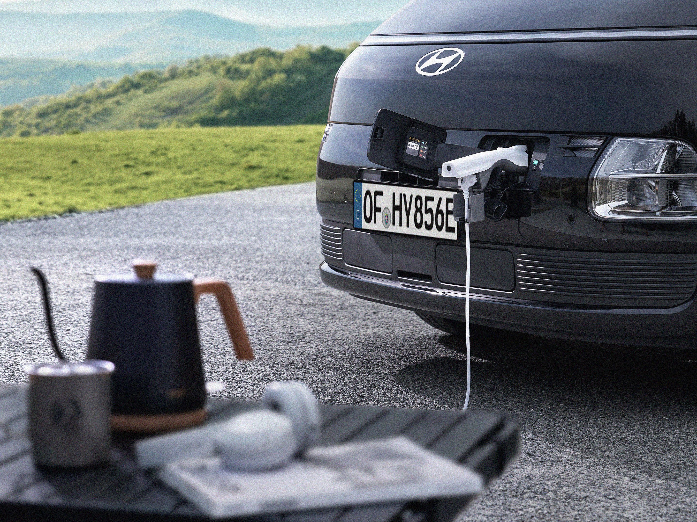 Hyundai STARIA Electric front charging port supplying power to an external device using Vehicle-to-Load (V2L) functionality.