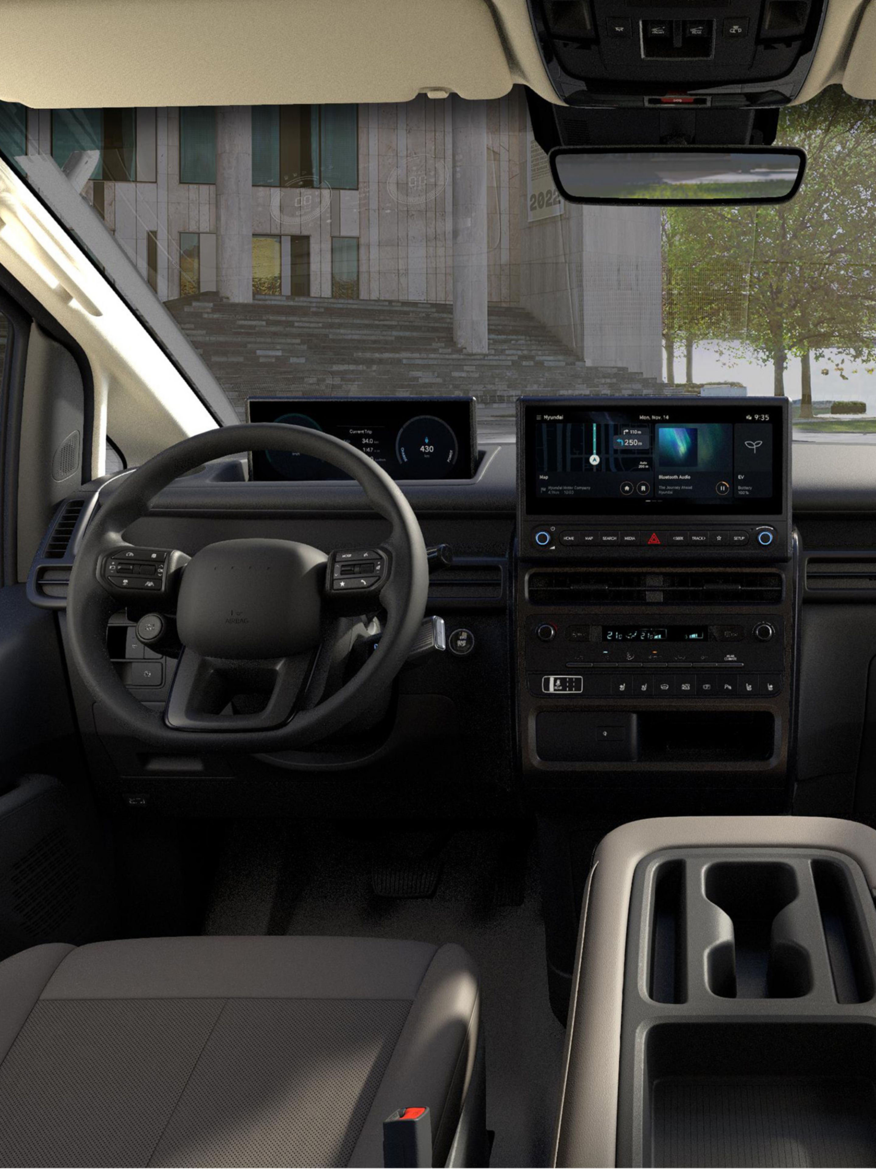Front interior of the Hyundai STARIA Electric showing dashboard layout, dual screens, and multifunction steering wheel.