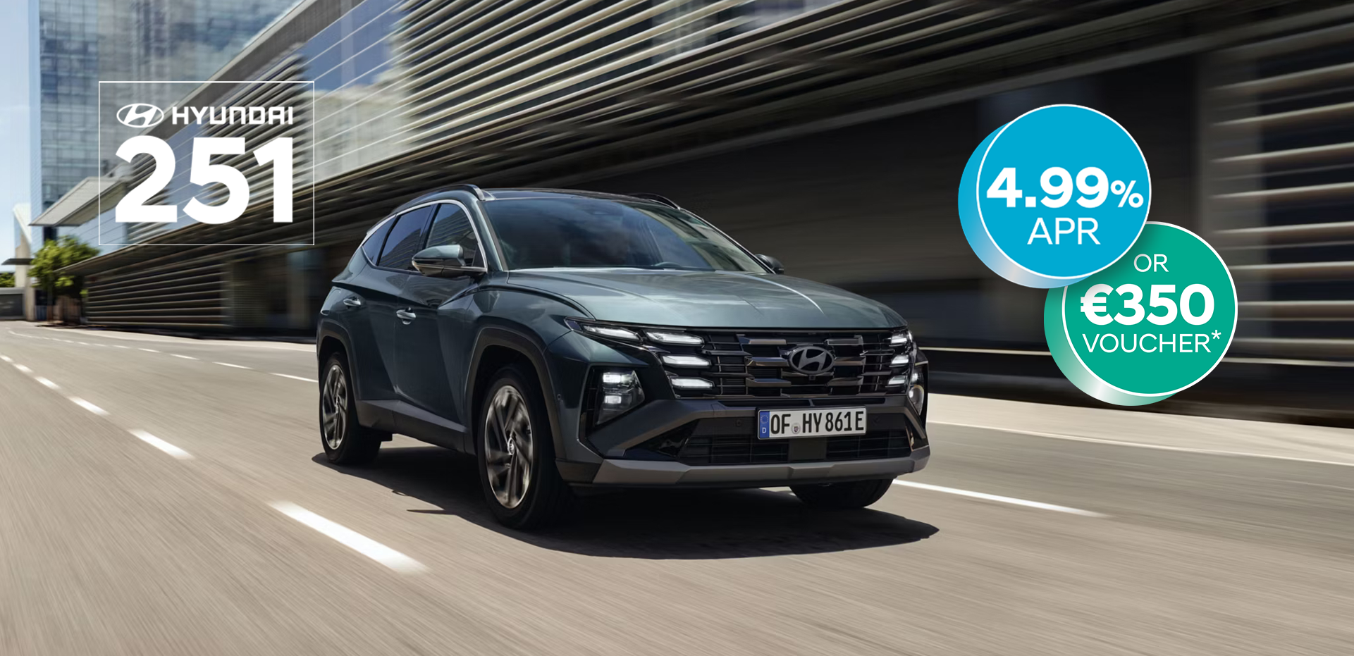 The Hyundai TUCSON Plug-in Hybrid driving down a city street with modern buildings visible.