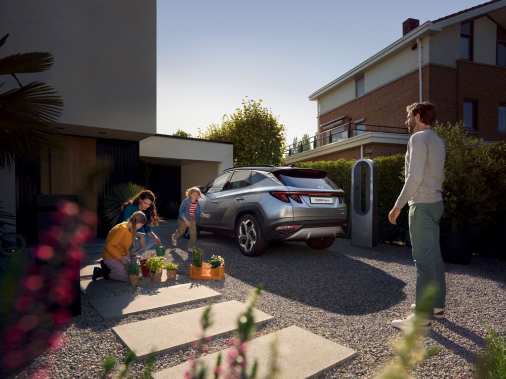 Family next of the all-new Hyundai TUCSON Plug-in Hybrid N Line in a housing area.